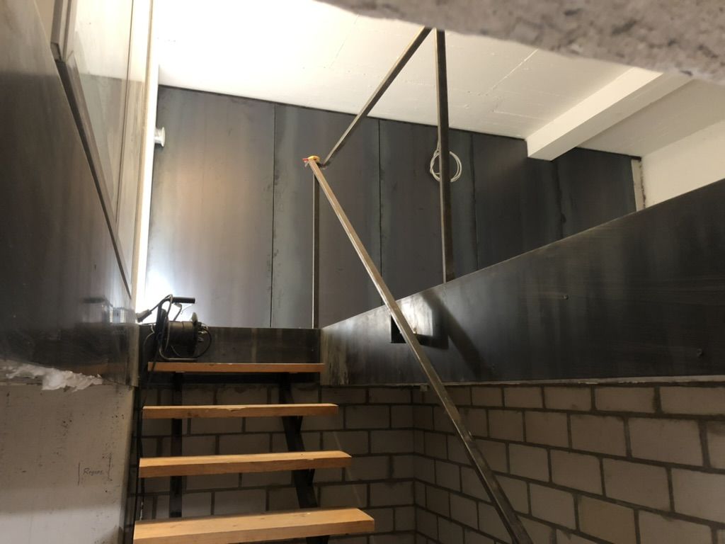 Treppe mit Holzstufen, Handlauf aus Edelstahl und Brüstung aus schwarzem Stahlblech.