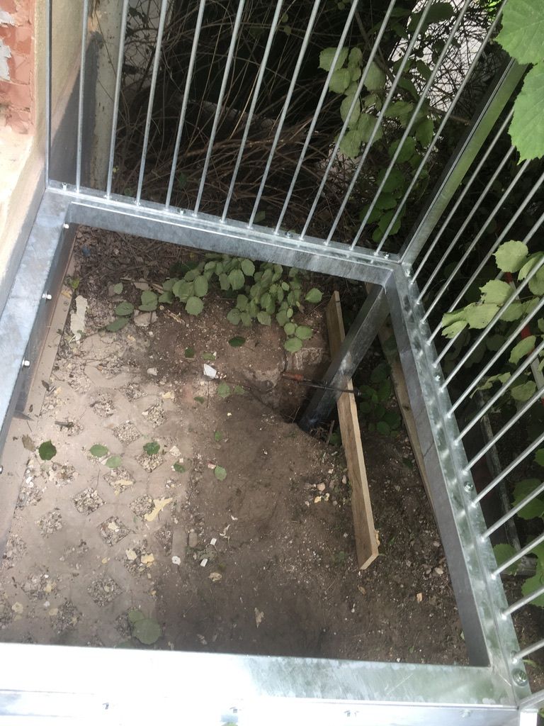 Feuerverzinkte Einfassung aus senkrechten Rundstäben um eine Erdfläche.