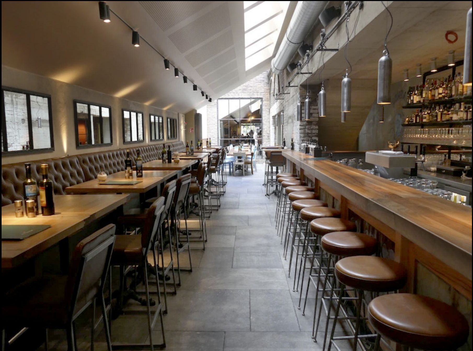 Restaurant mit Spiegeln in schwarzen Stahlrahmen über den Sitzbänken und einer Thekenfront.